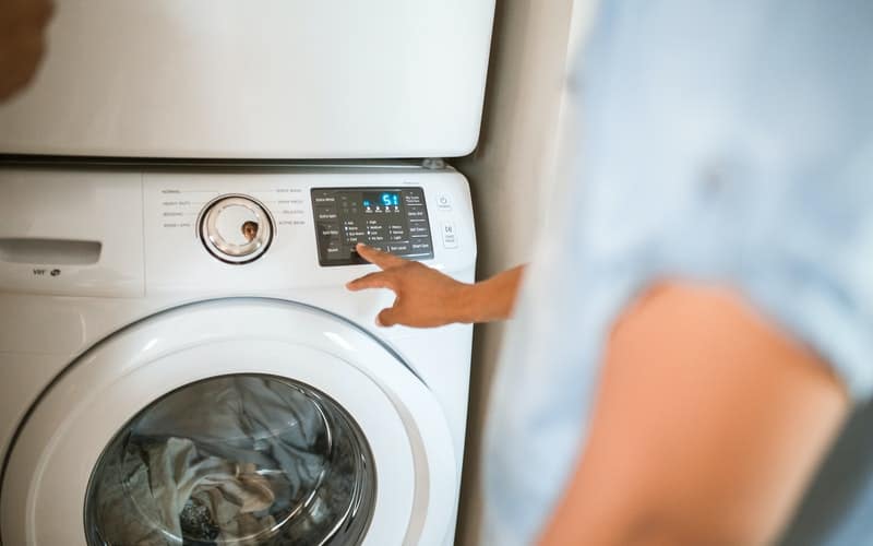 person pressing a button on a washing machine