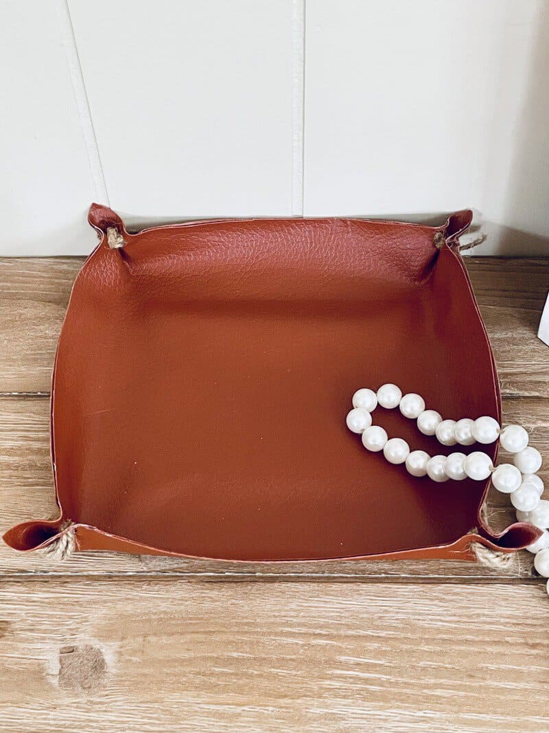 leather tray with white necklace in it