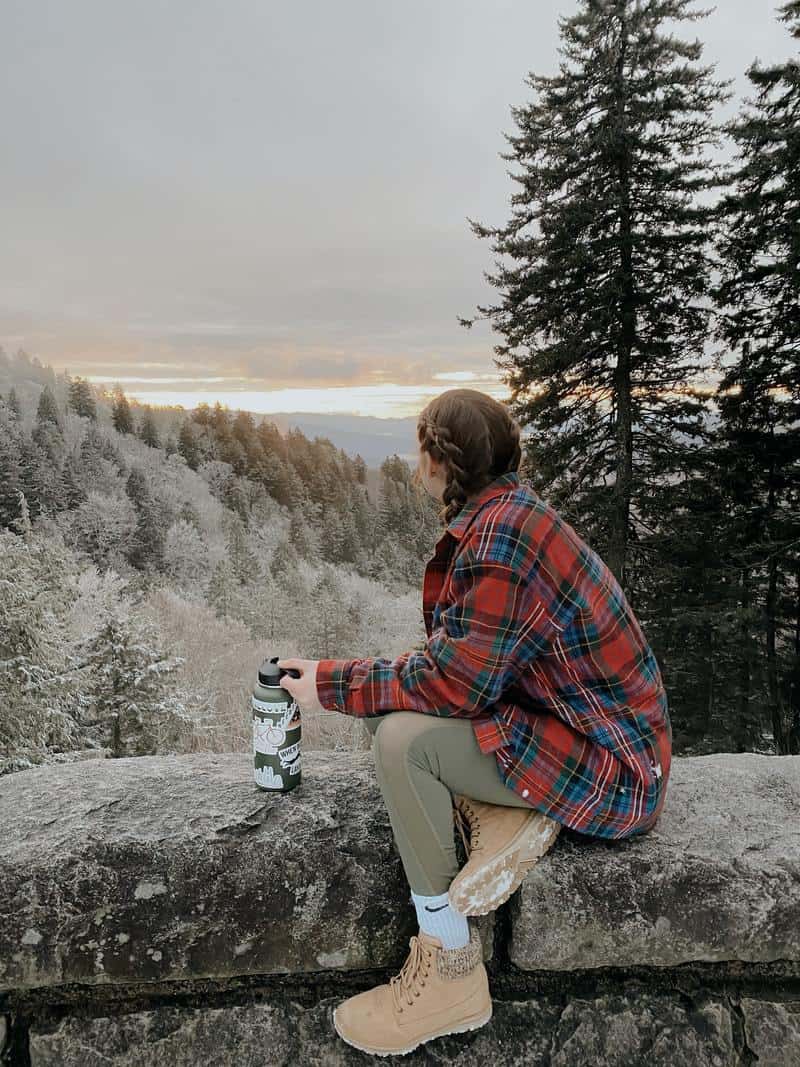 a woman wearing hiking clothes sitting on a rock