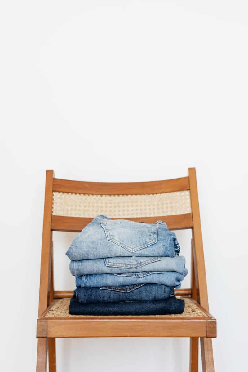 Wallflower jeans stacked on a brown chair