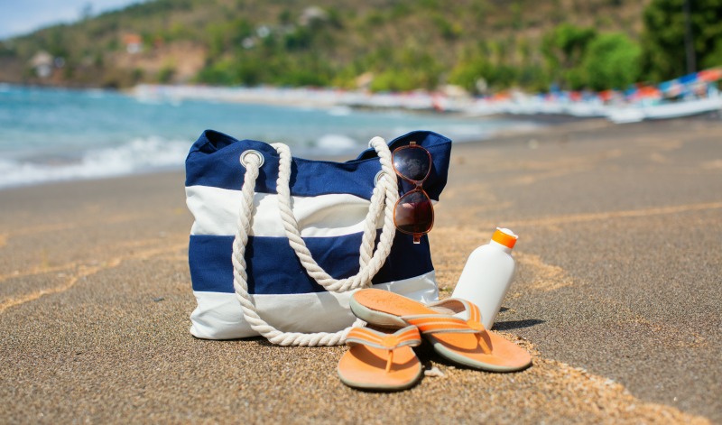 a tote bag and sandals on the sand