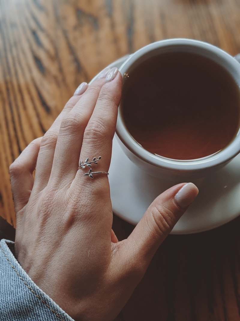a woman wearing pink nail polish holding a cup of coffee