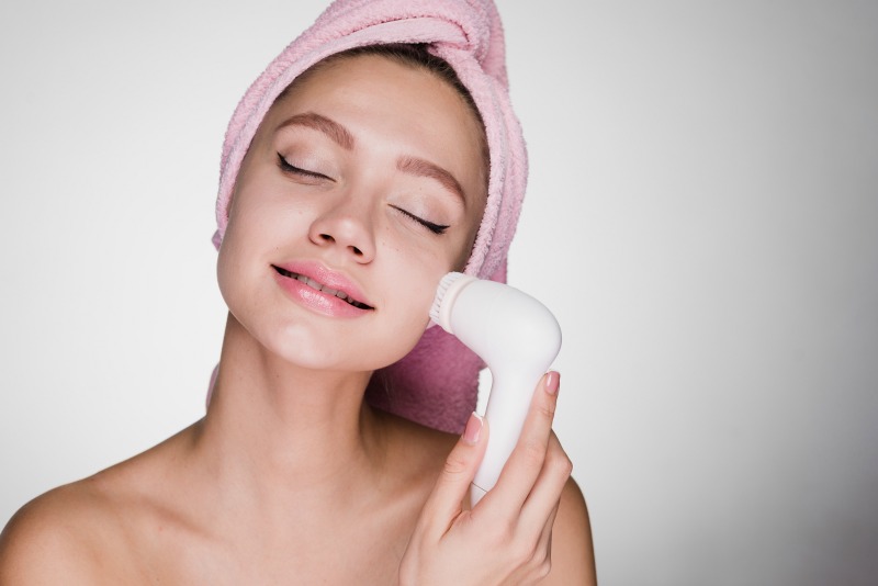 a woman using an exfoliating face brush