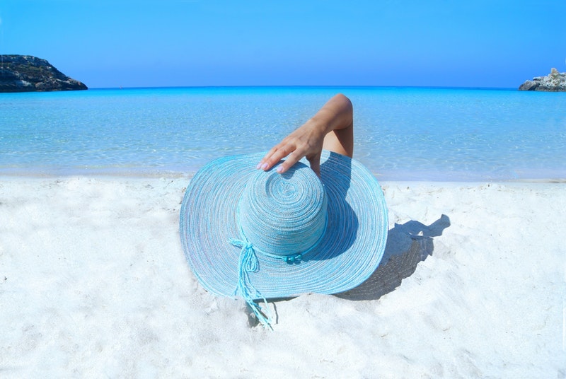 woman with blue hat on white sands on the beach