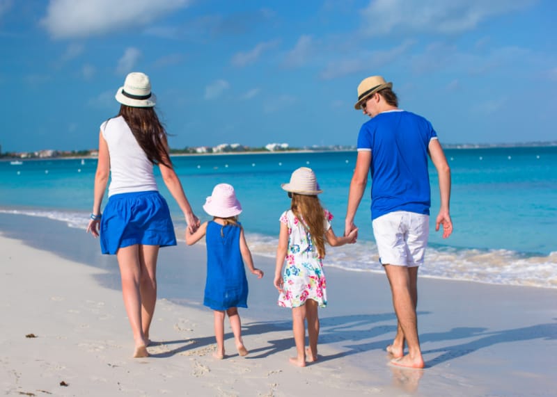 A family walking on the beach wearing blue and white