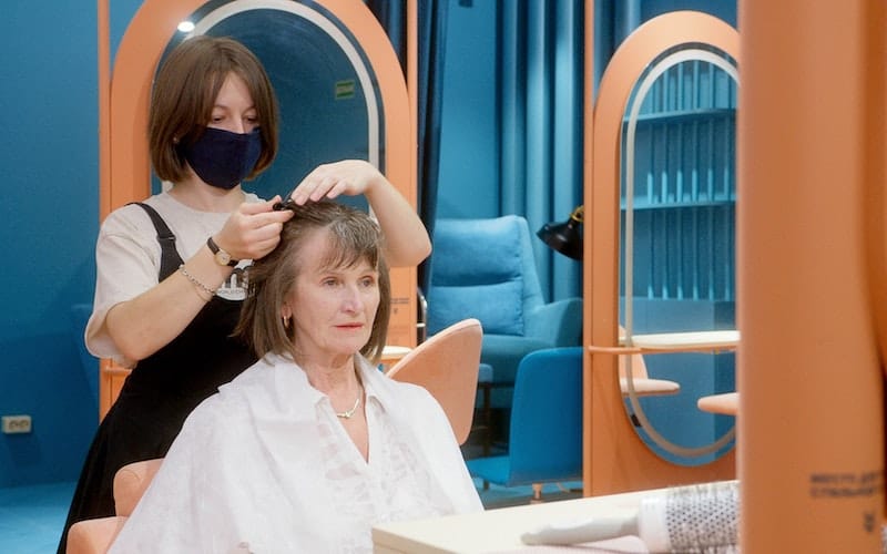 woman in a chair having her bangs cut