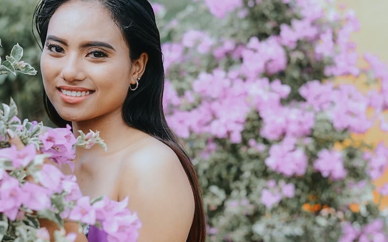 Asian woman in front of purple flowers 