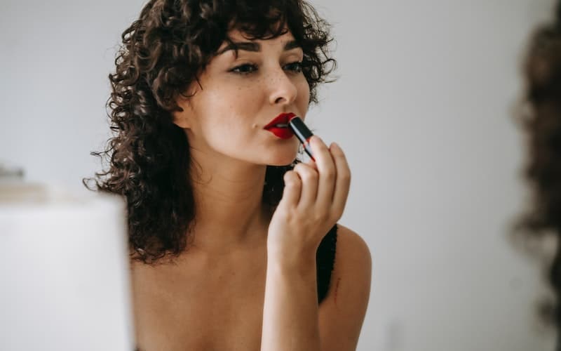 woman with dark skin applying lipstick