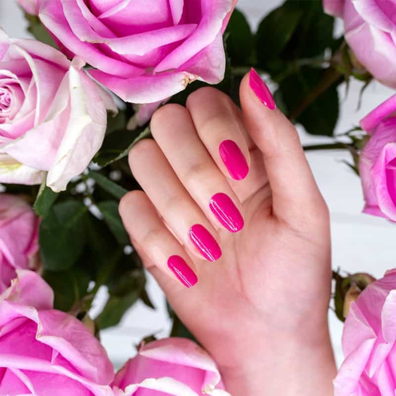 a woman with pink nails against a background of pink flowers