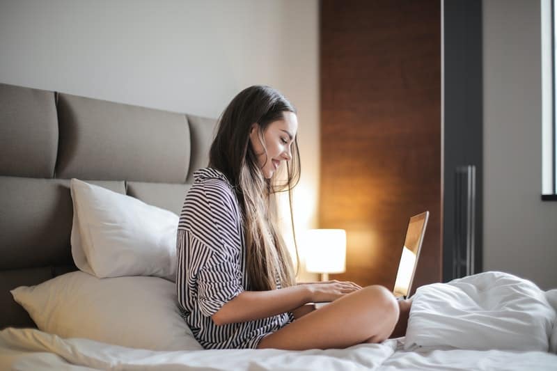 a woman sitting on a bed shopping online