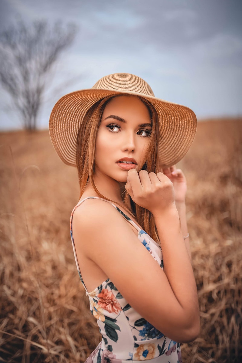 a beautiful woman wearing a straw hat in a field