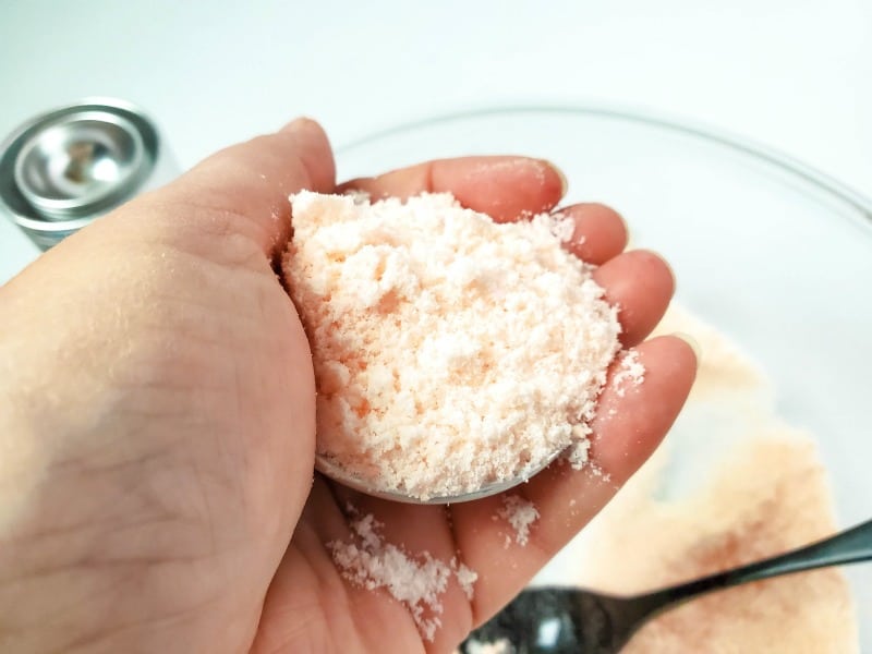 a hand holding a bath bomb mold with ingredients