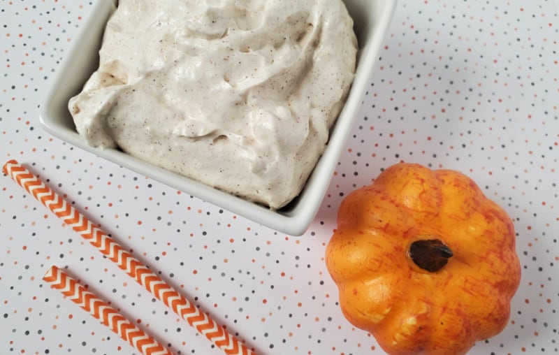 a whipped body butter in a white bowl with a pumpkin near it