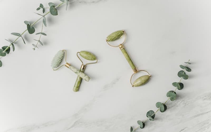 facial rollers on a white counter with eucalyptus