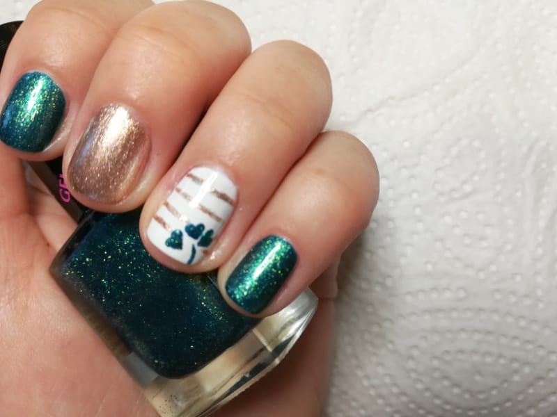a woman wearing shamrock nail designs holdng a bottle of polish