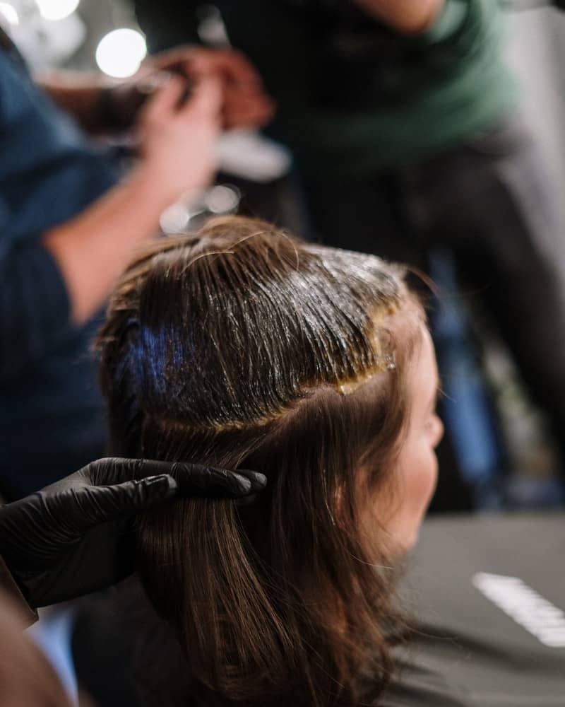 a woman applying henna hair dye to her hair