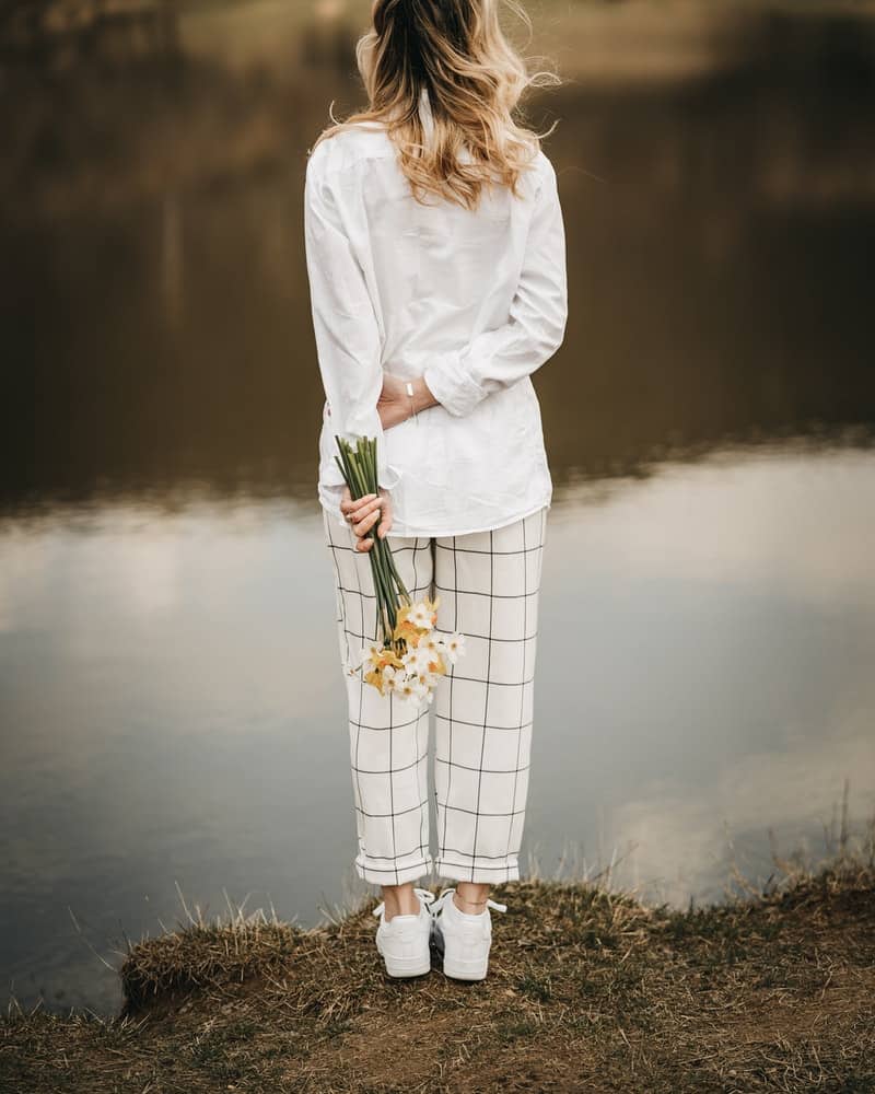 a woman wearing white linen pants near the river