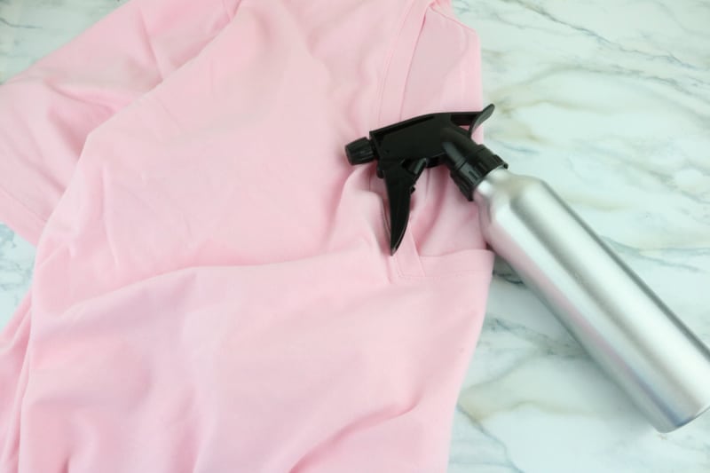 a homemade wrinkle spray laying on a pink shirt