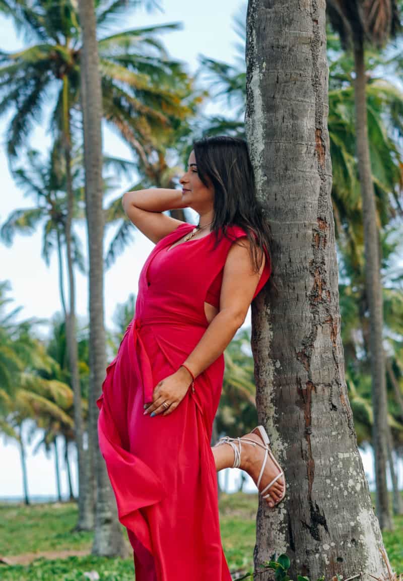 a woman wearing a red dress near a palm tree