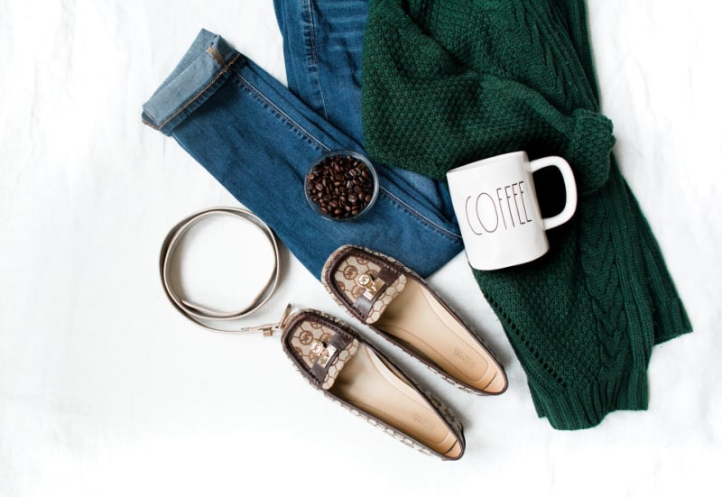 a flat lay of a green sweater, jeans and flats