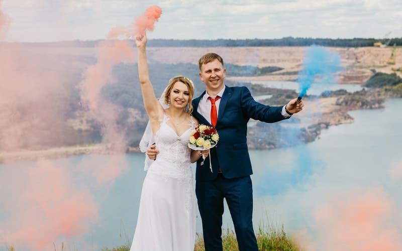 a bride and groom holding smoke sticks