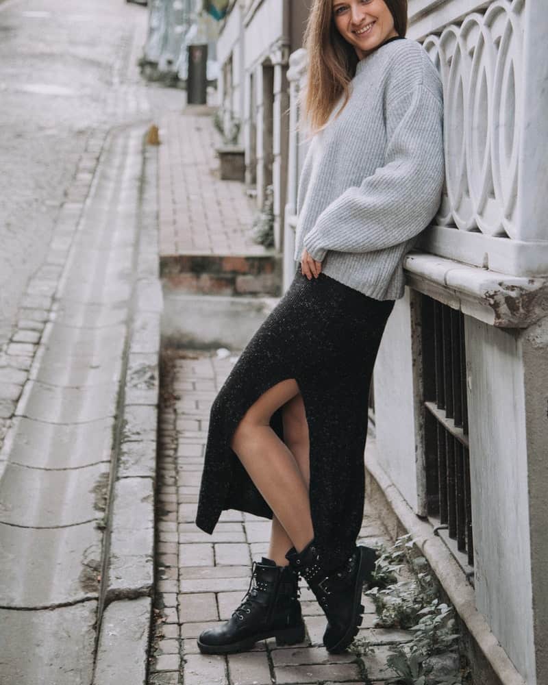 a woman wearing combat boots and a skirt with a sweater
