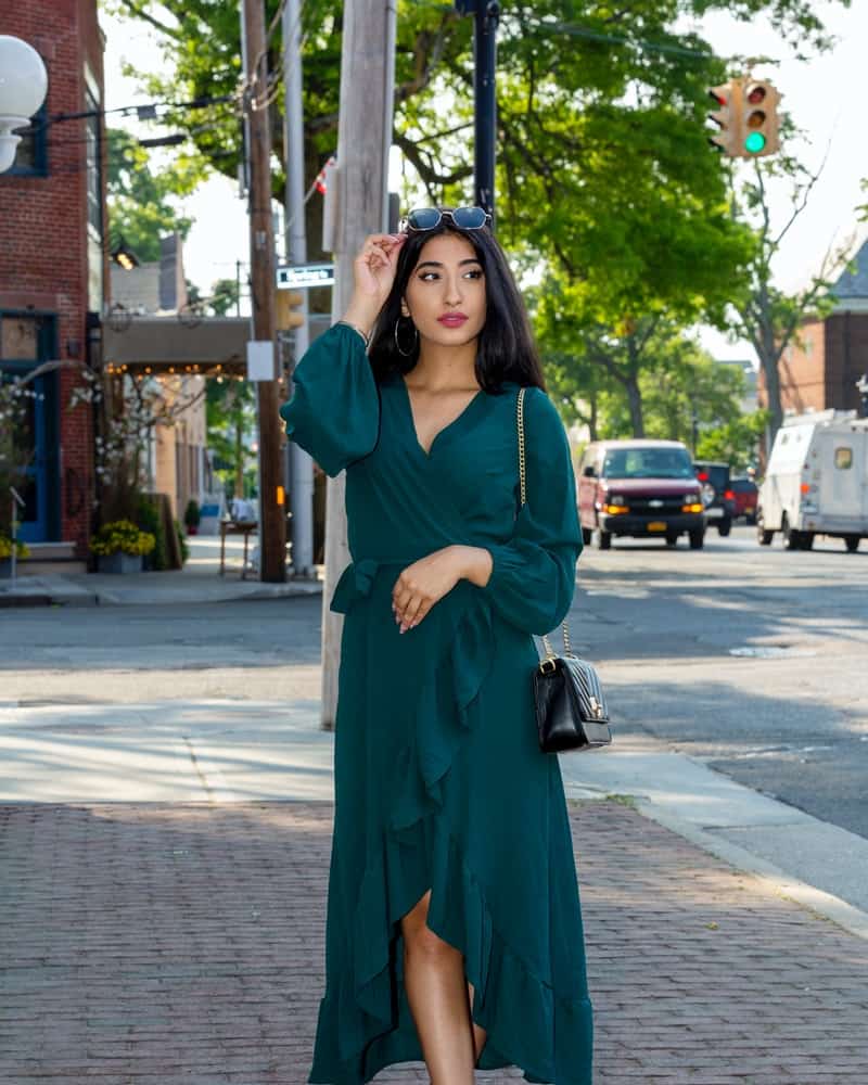 a woman wearing a green dress standing on the street