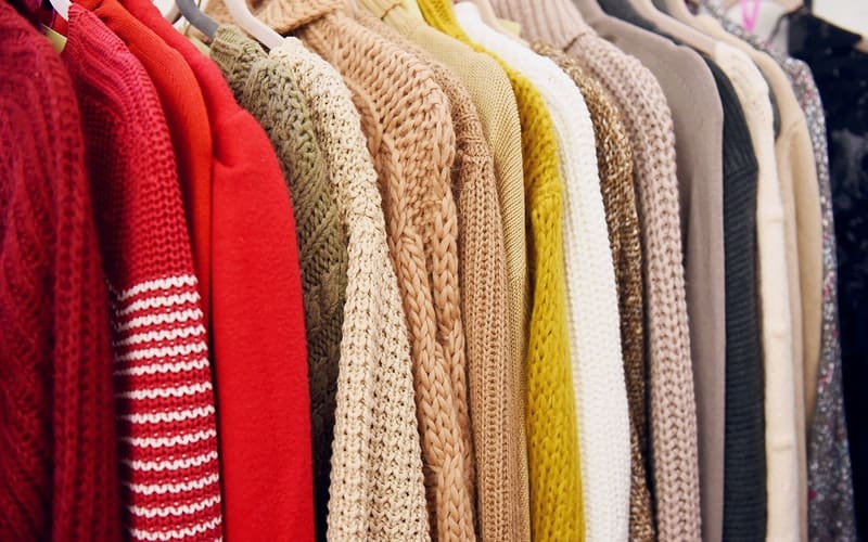 wool sweaters hanging in a closet