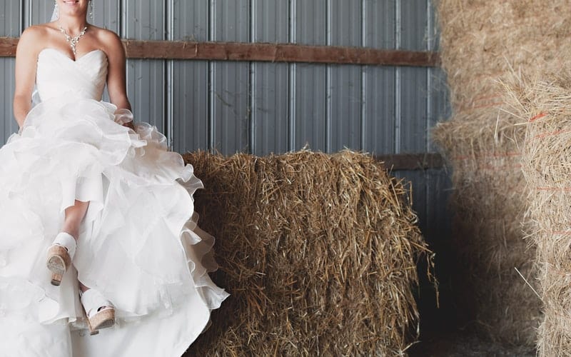 a woman in a wedding dress sitting on hay bales