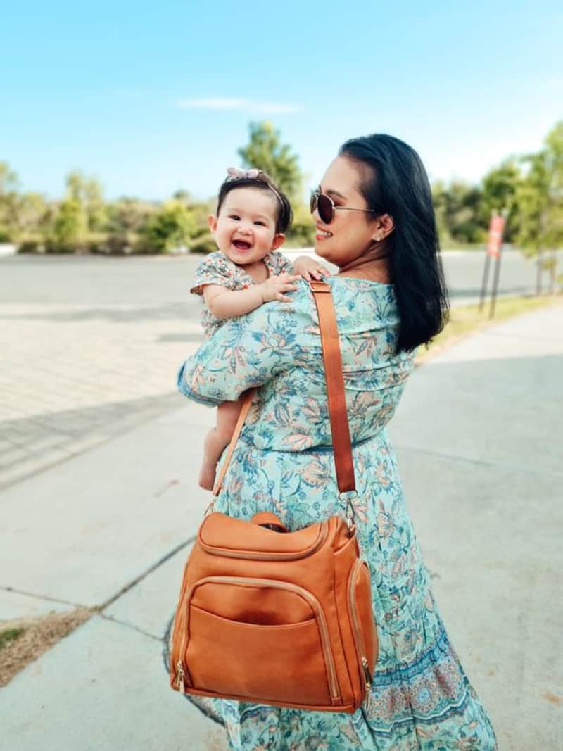 a woman holding a baby and a diaper bag