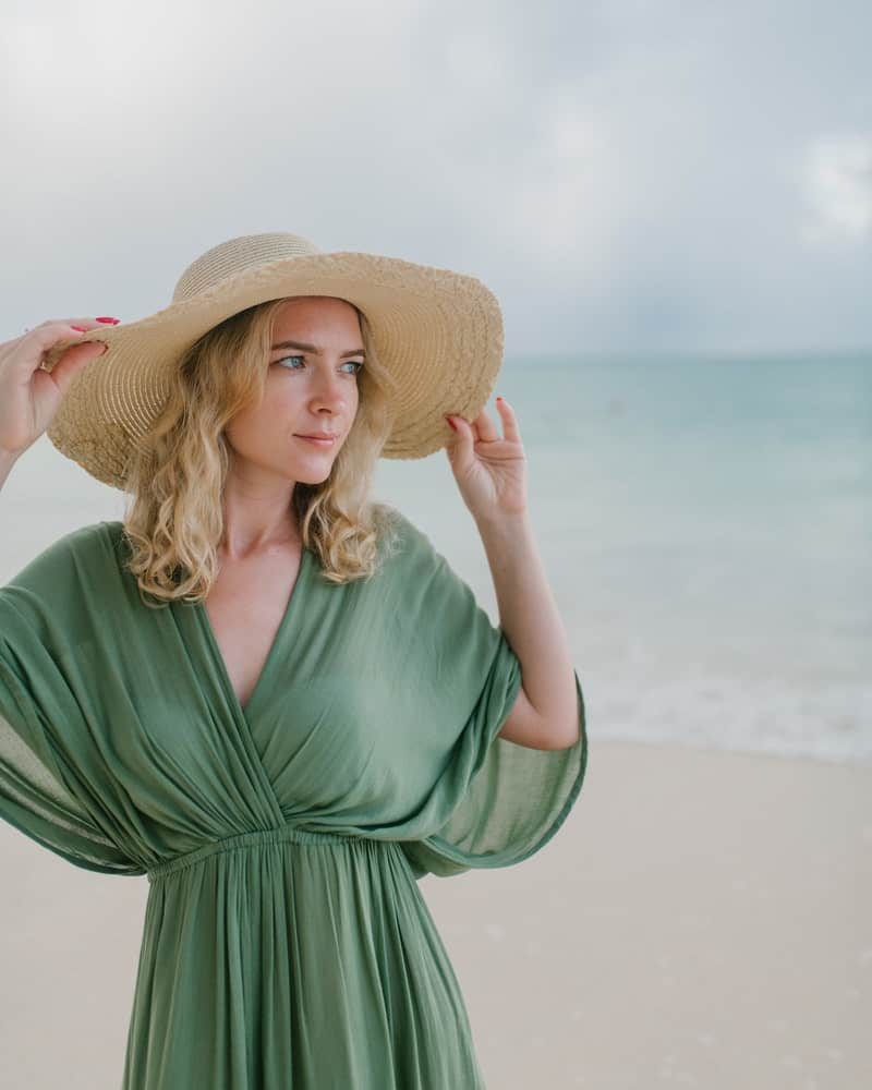 a woman wearing a green gown and a beach hat