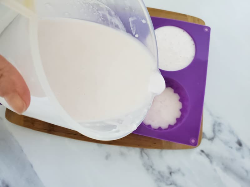 pouring soap base into a purple mold