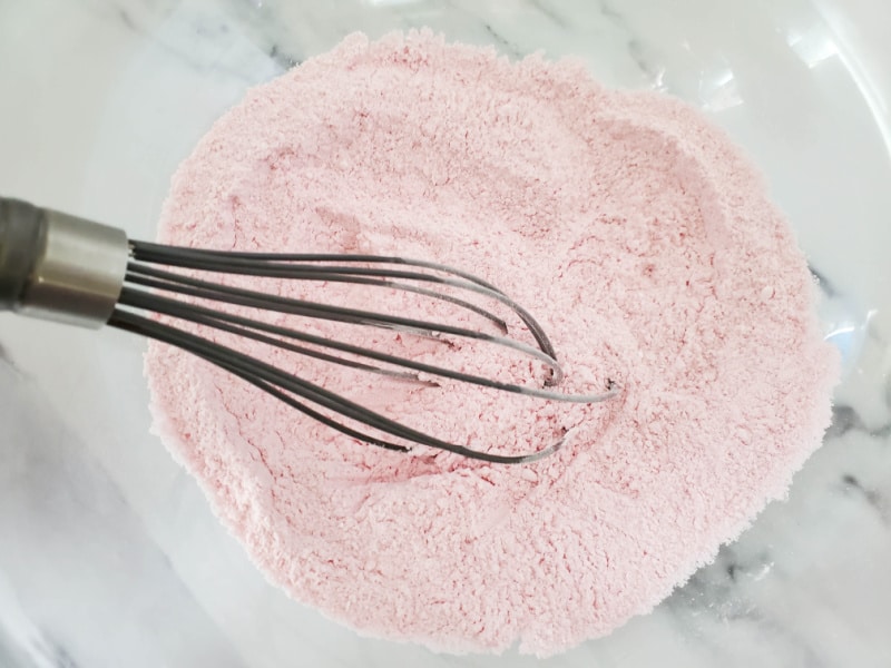 whisking pink powder in a glass bowl