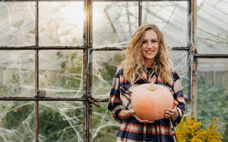 a woman wearing flannel holding a pumpkin