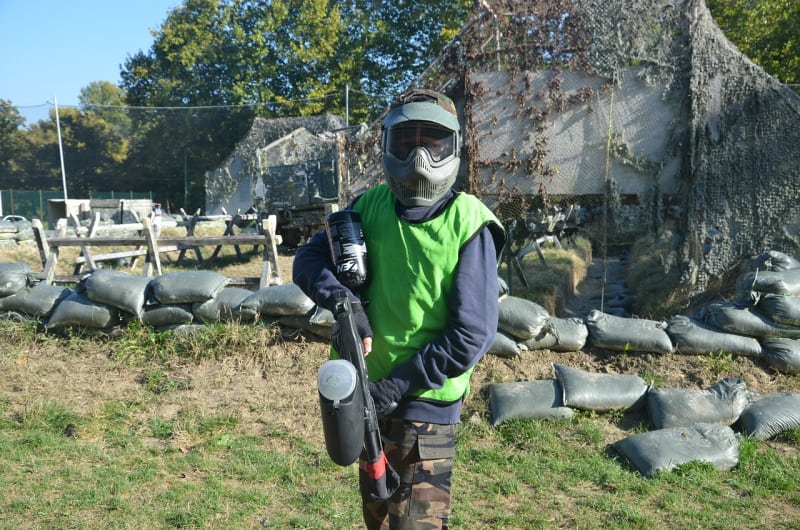 a person wearing green paintball gear in a field