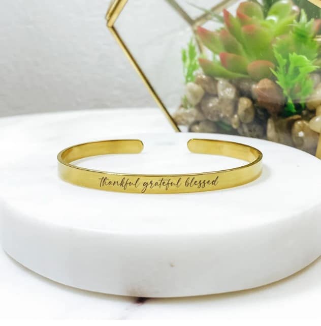 a gold bracelet on a white stand