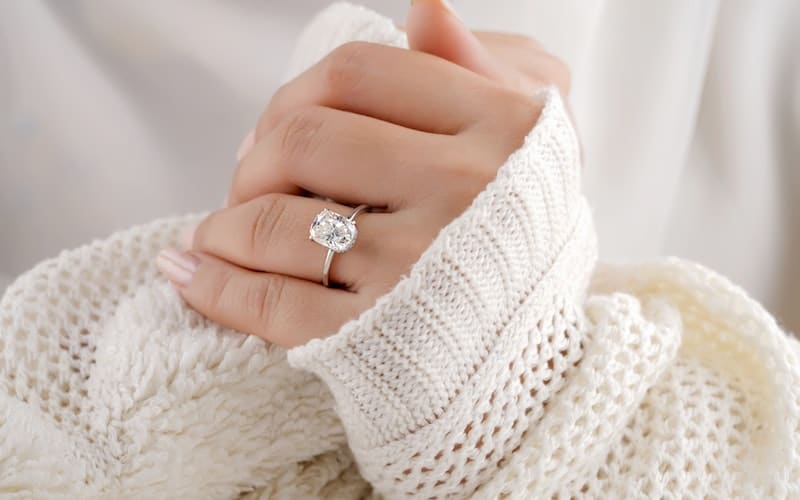 a woman wearing a white sweater and a faux diamond ring