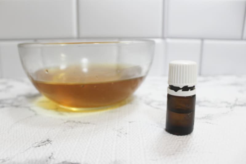 an essential oil bottle near a bowl of oil