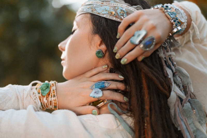 beautiful young stylish woman with boho accessories and gem stone rings at sunset