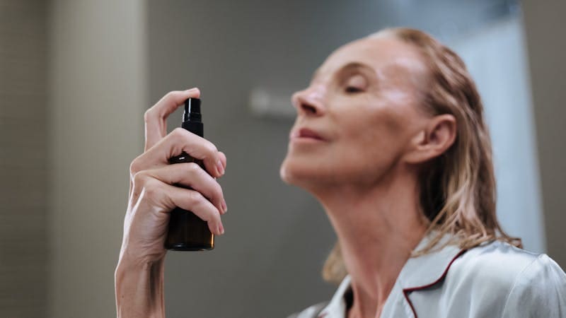 woman spraying skin care on her face