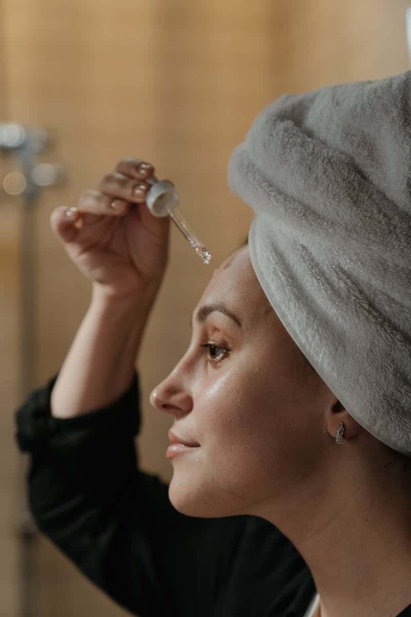 a woman applying a serum to her forehead