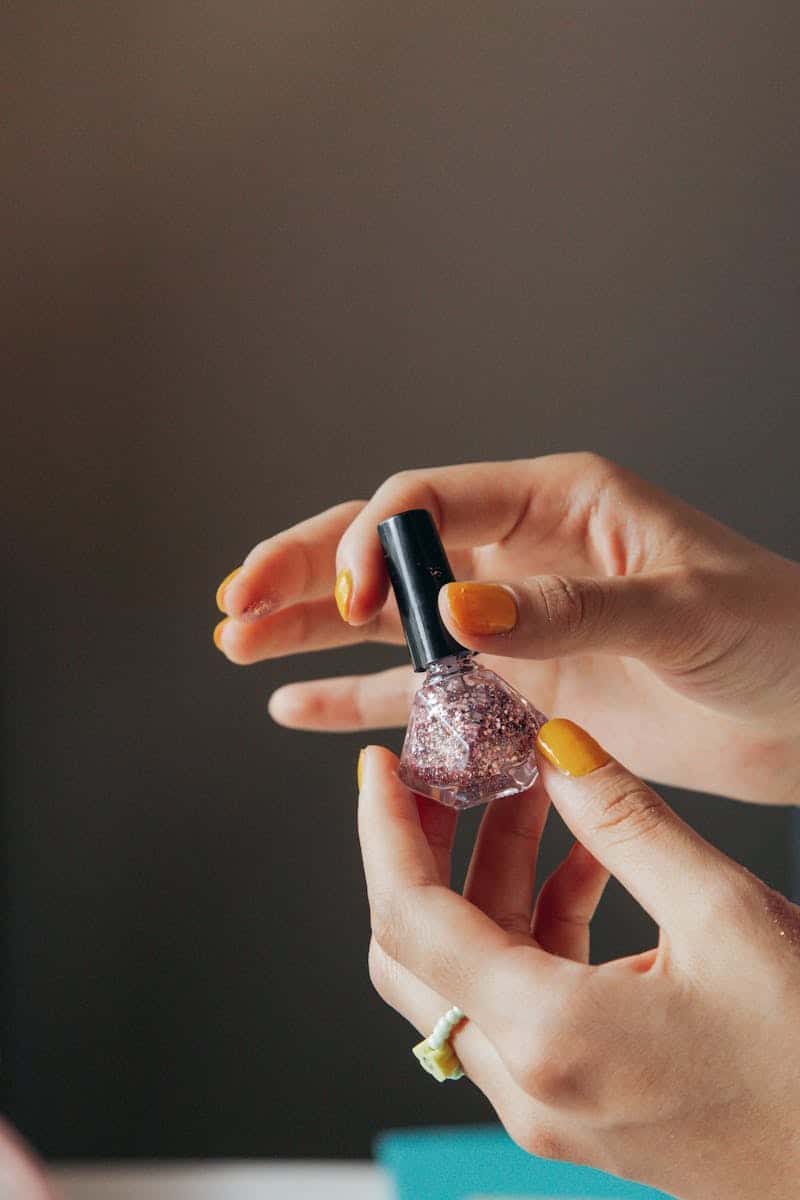 person holding a bottle of pink nail polish