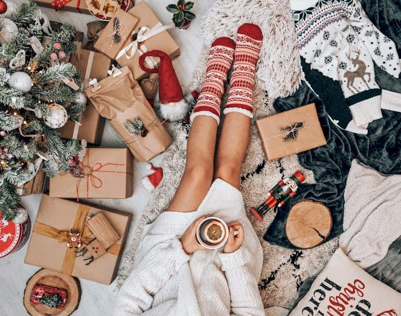 woman wearing Christmas socks sitting surrounded by presents