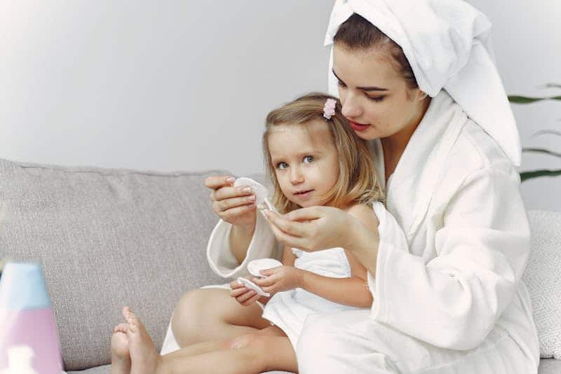 woman in white robe hugging girl in white towel