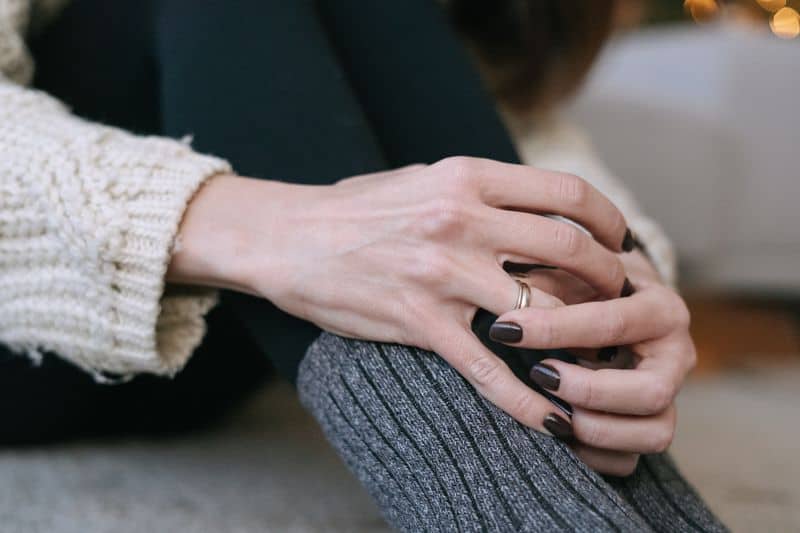 woman wearing a cable sweater and chocolate brown nail polish