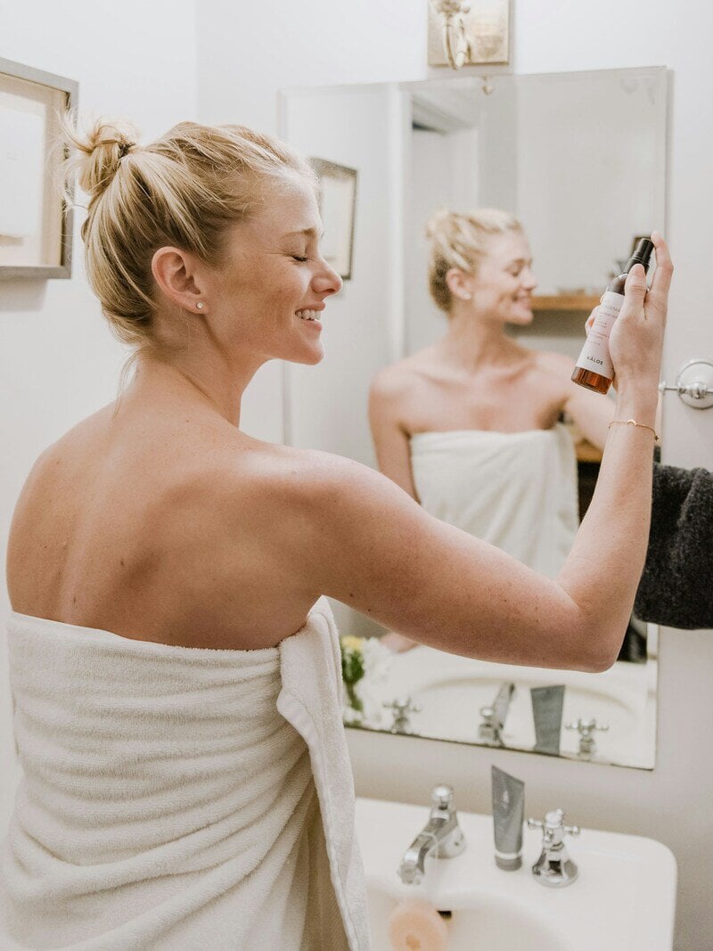 woman spraying product on skin